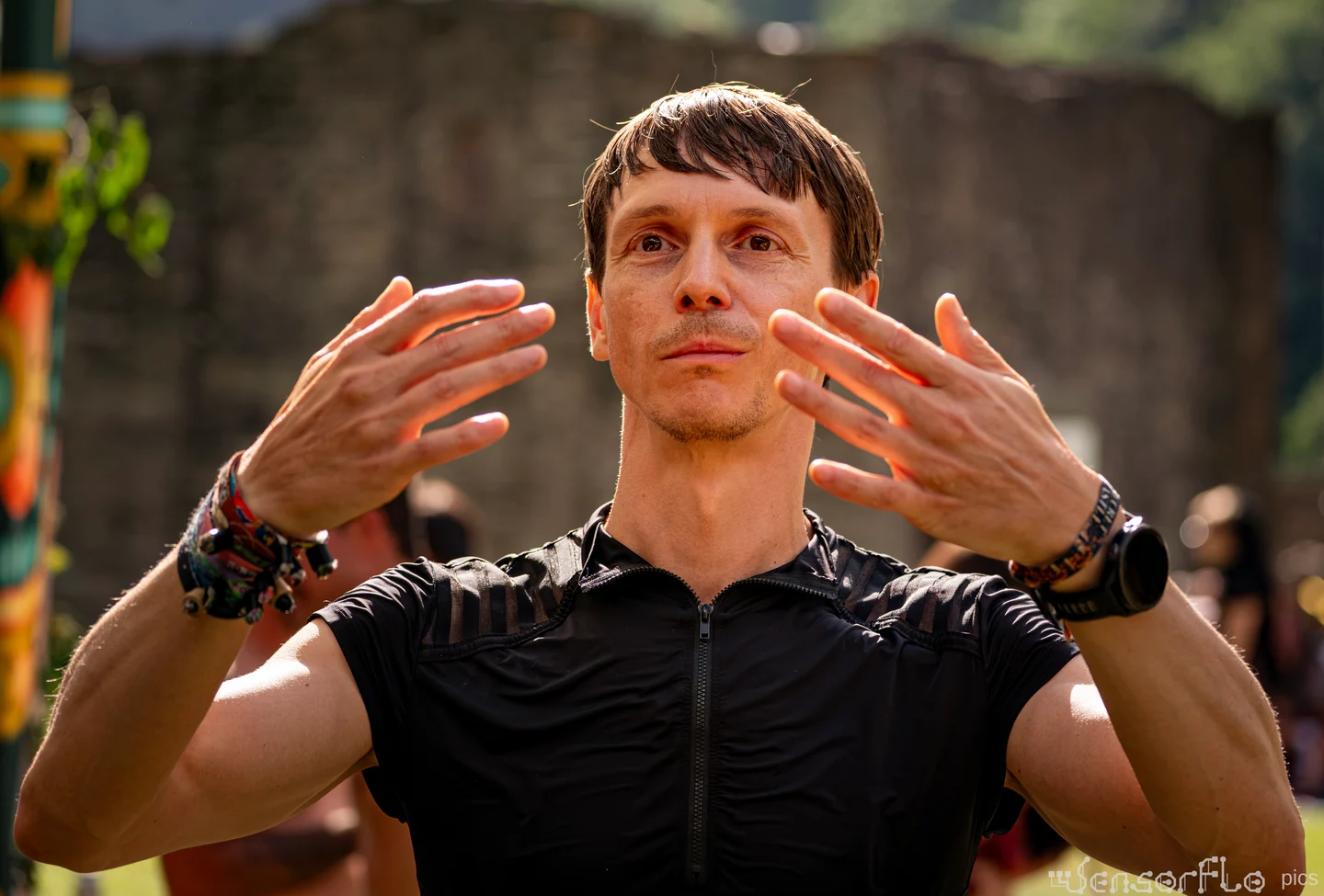 Denis Pingin outdoors, with both hands raised in front of him.